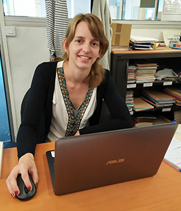 portrait de Céline Rkalovic derrière son bureau et ordinateur.